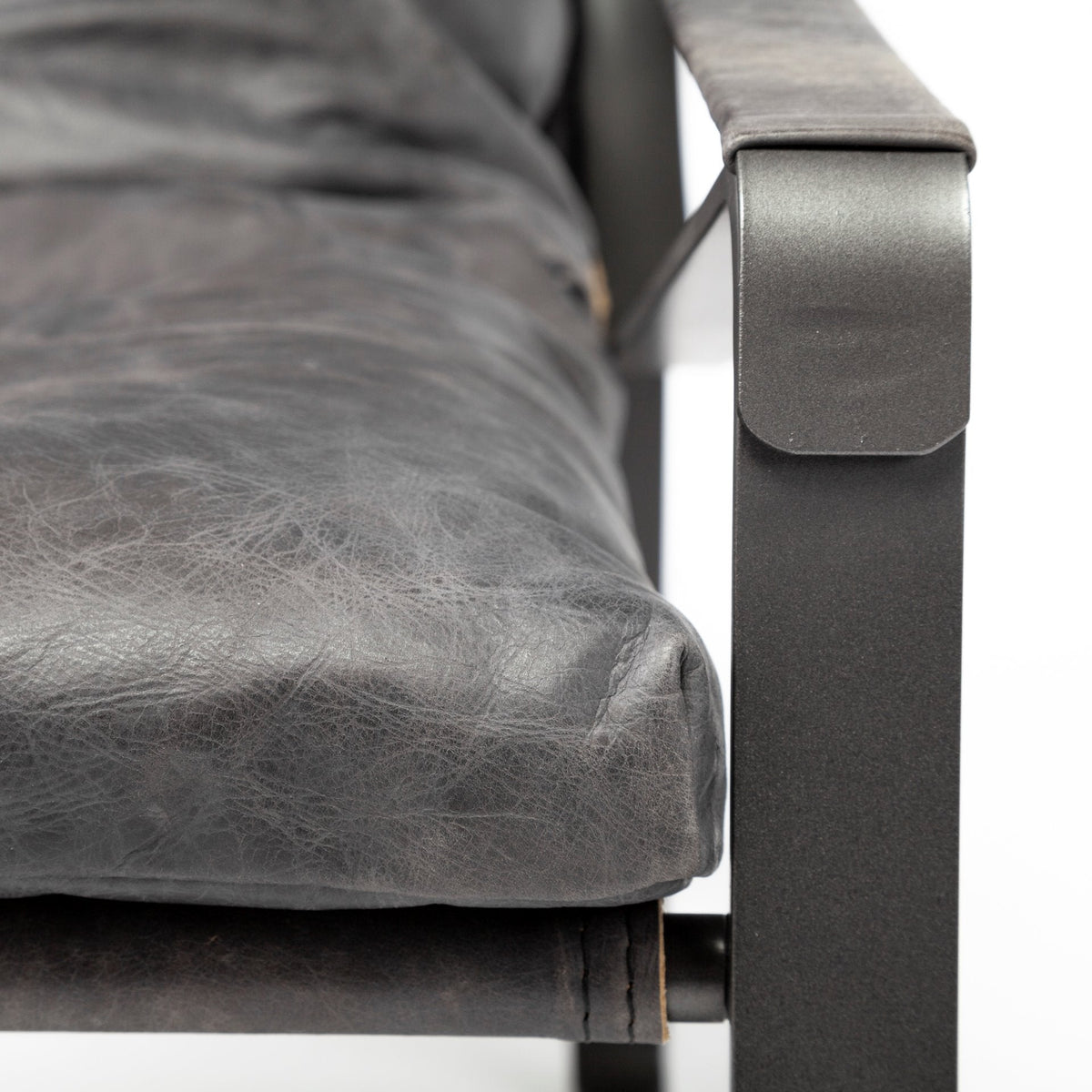 Close-up of the black leather upholstery, leather-wrapped arm and metal frame.