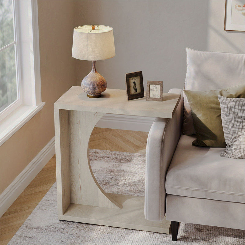 Beige C-shaped side table with a lamp beside a sofa.
