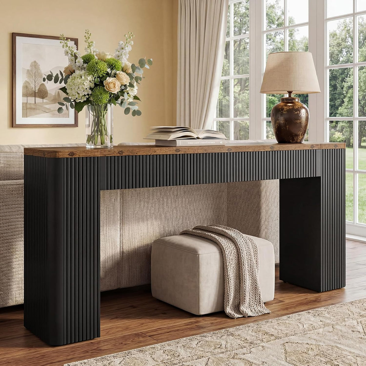 Brown and black fluted console behind a sofa near a bright window.