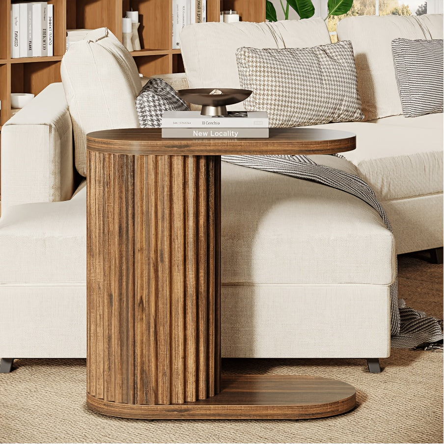 Angled view of the rustic brown table’s projecting oval top and lower foot.