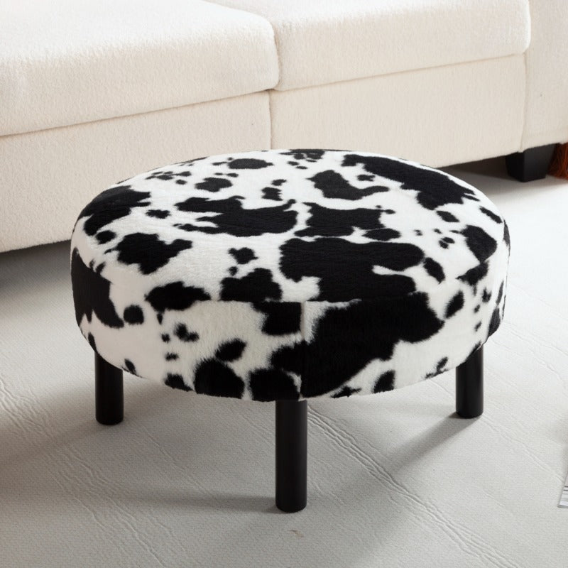 Cow-pattern ottoman shown beside a cream sofa