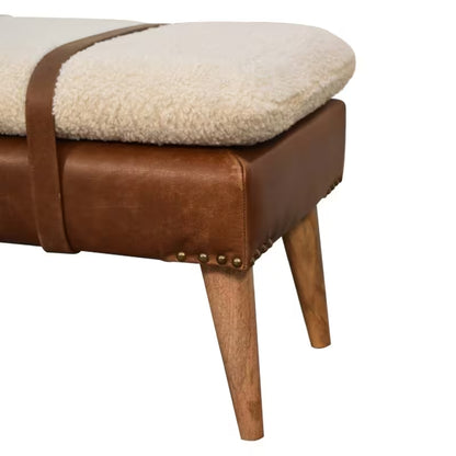 Close view of bench corner showing textured cream cushion, brown base, and nailhead accents