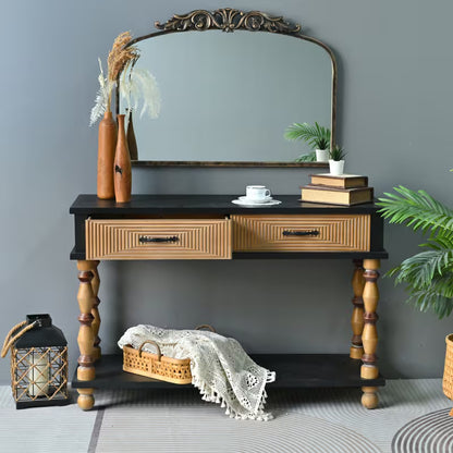 Front view of the black console with natural-tone patterned drawers and turned legs.