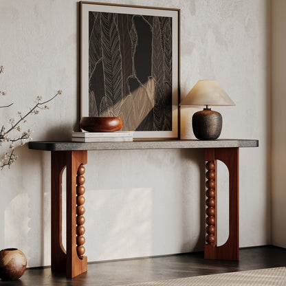Console with a dark top and warm brown beaded supports styled below framed artwork.