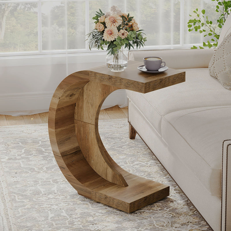 Rustic brown curved C-shaped table beside a cream sofa.