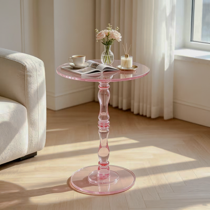 Pink transparent acrylic pedestal side table with a shaped stem beside a sofa