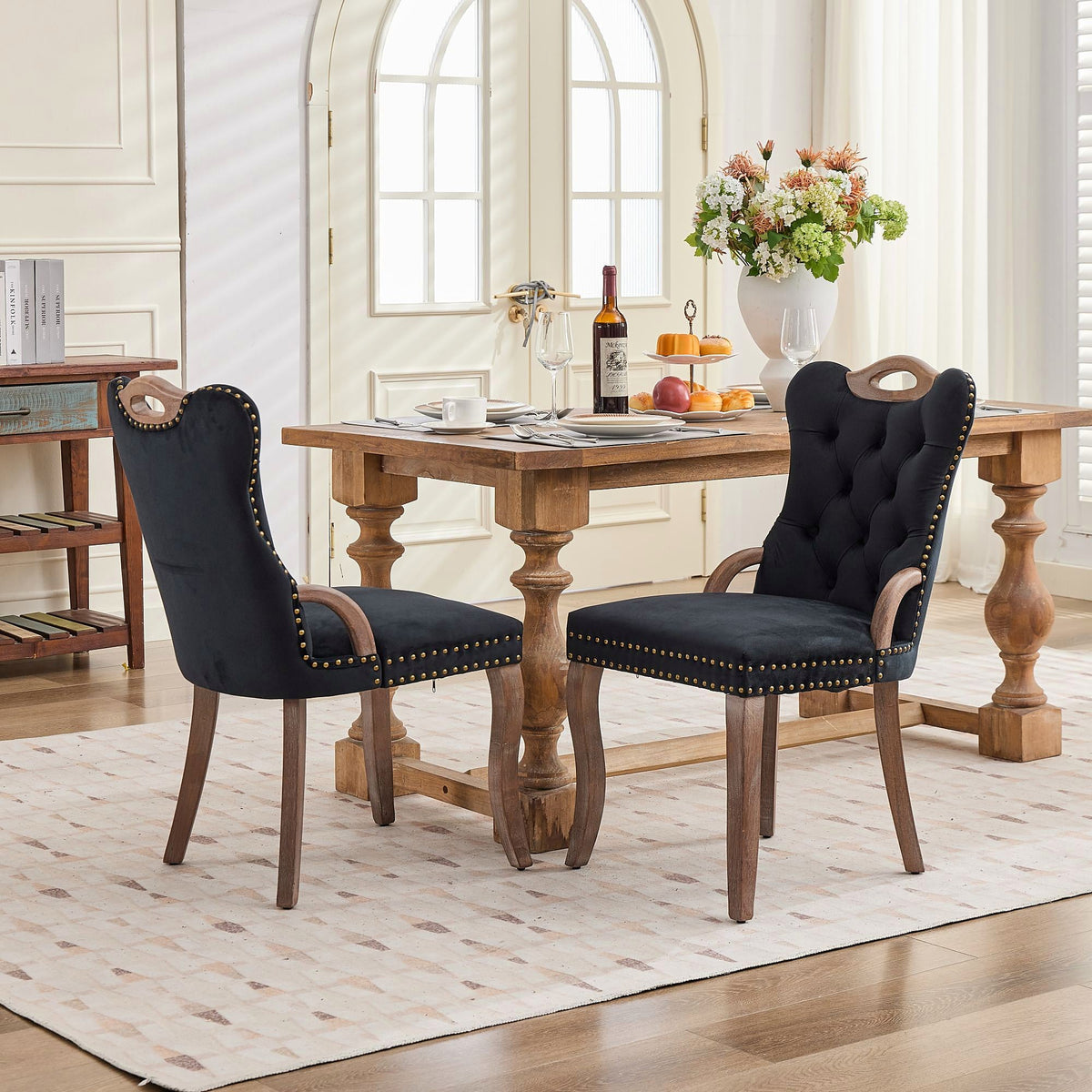Black velvet dining chair with a tufted back, wood handle, and curved wood legs