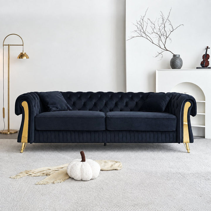 Black velvet Chesterfield sofa with gold-tone arm accents in a light living room