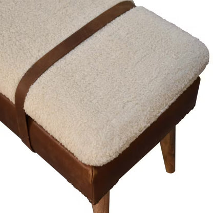 Overhead detail of cream boucle-style cushion crossed by two brown decorative straps