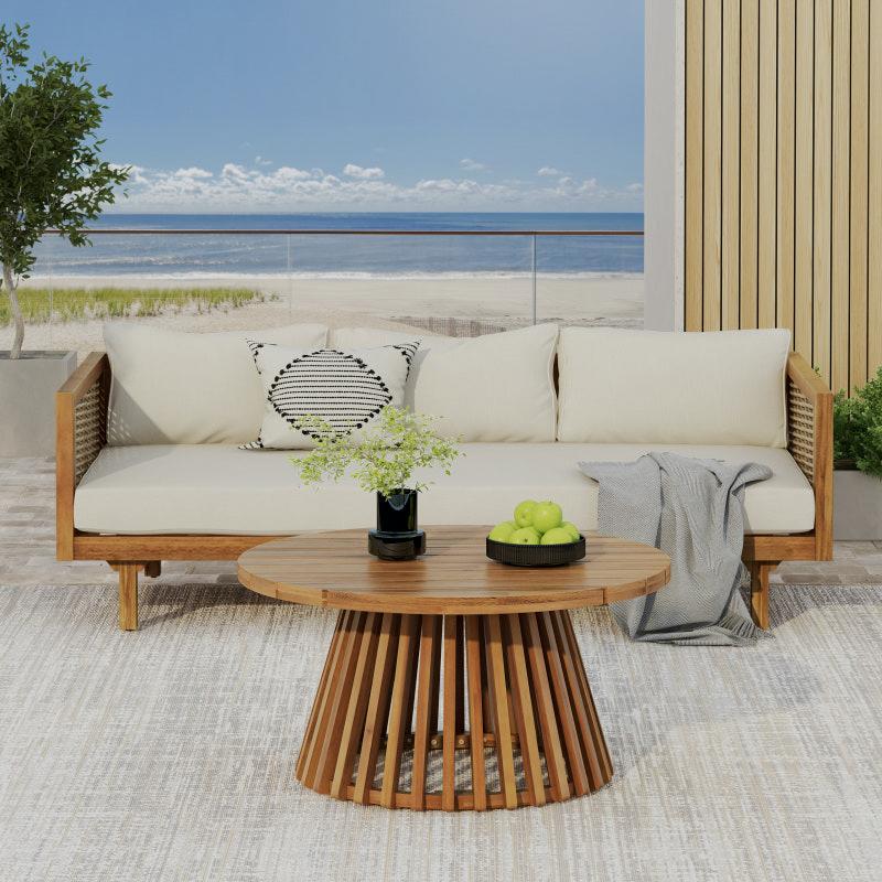 Patio sofa and round slatted-base table on a rug in a coastal setting