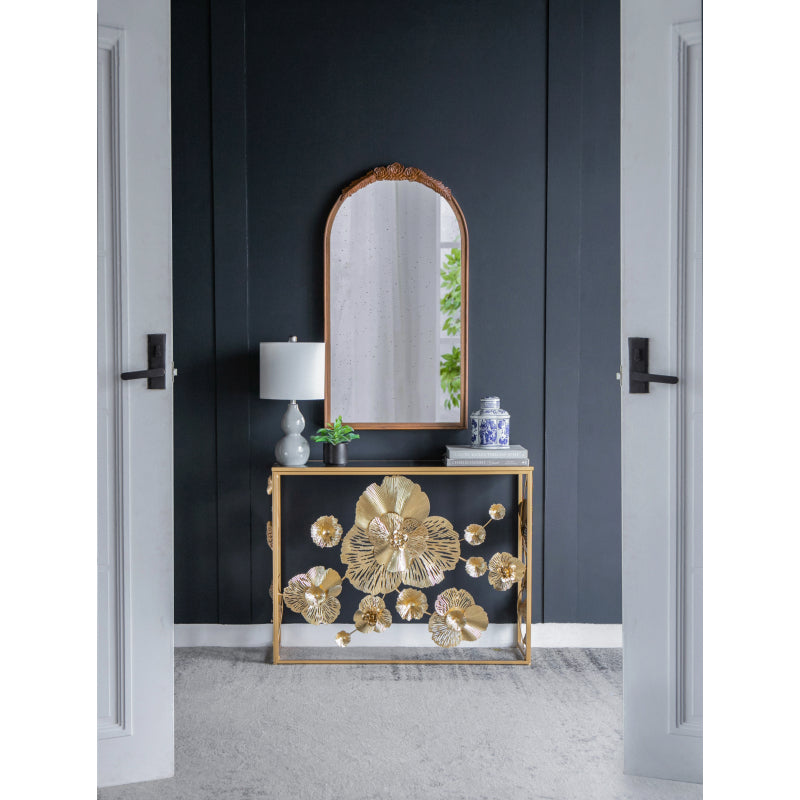 Gold floral console styled at the end of an entry hallway.