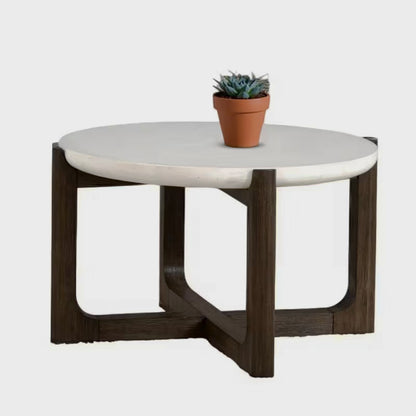 Round white stone-look coffee table with a dark crossed trestle base on a white background