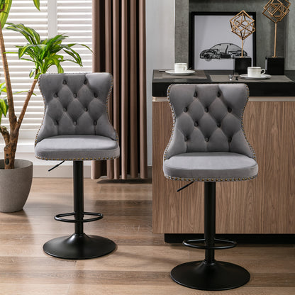 Two gray velvet swivel bar stools with circular footrests