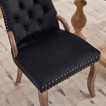 Black velvet dining chair with a tufted back, wood handle, and curved wood legs