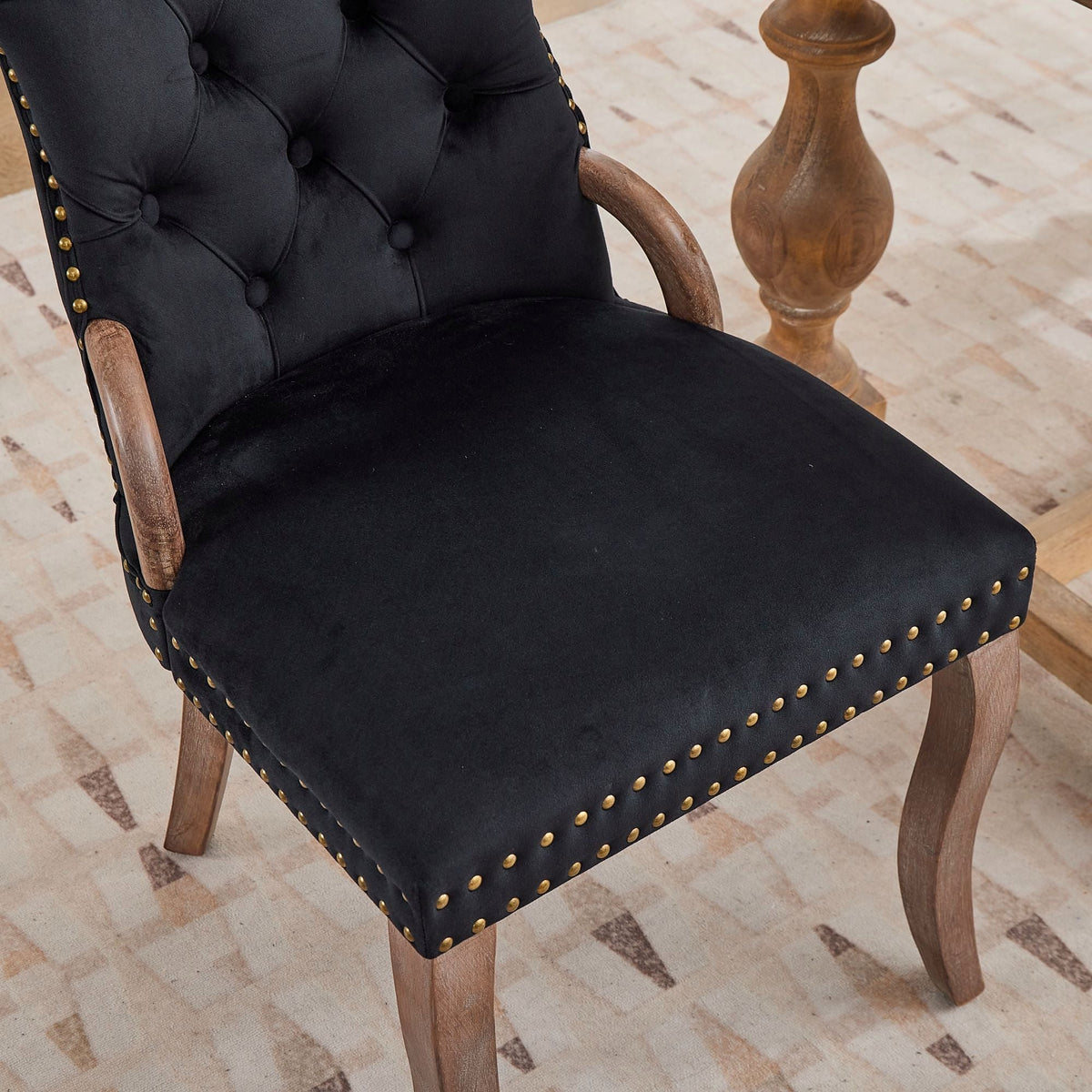 Black velvet dining chair with a tufted back, wood handle, and curved wood legs