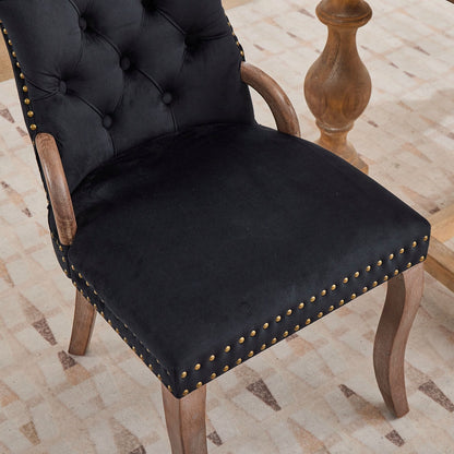 Black velvet dining chair with a tufted back, wood handle, and curved wood legs