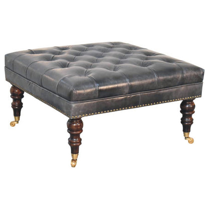 Three-quarter view of the black ottoman's button-tufted cushion