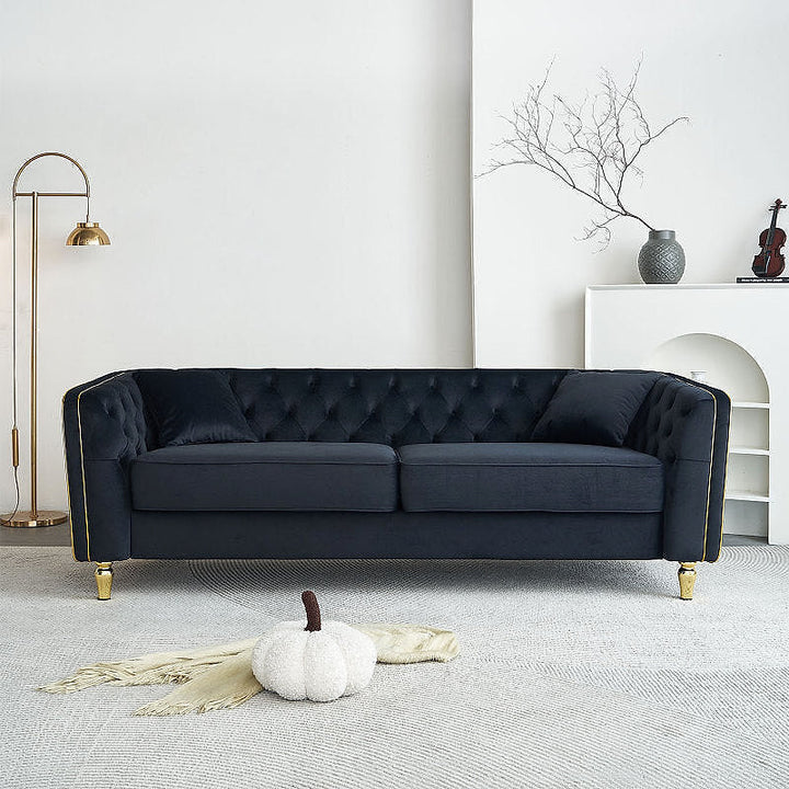 Lucien black tufted sofa with gold-tone piping in a living room