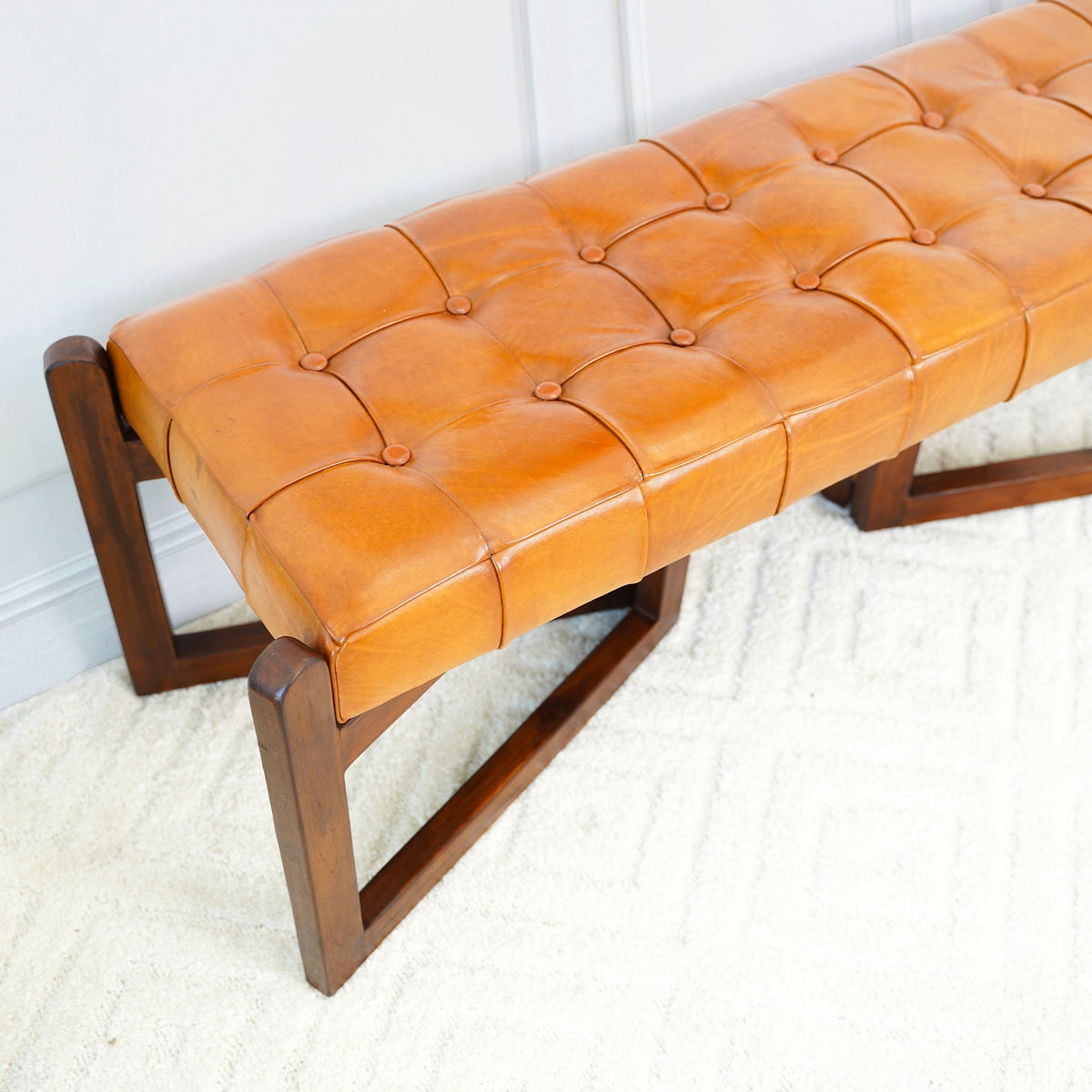 Close view of the tan bench's button-tufted seat