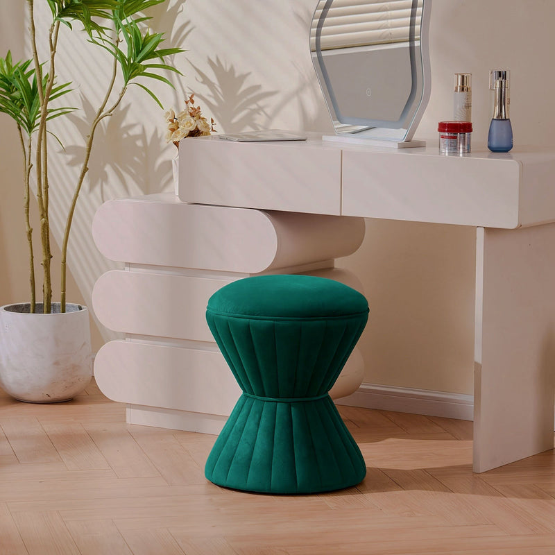 Teal velvet hourglass-shaped ottoman with pleated upholstery beside a vanity table