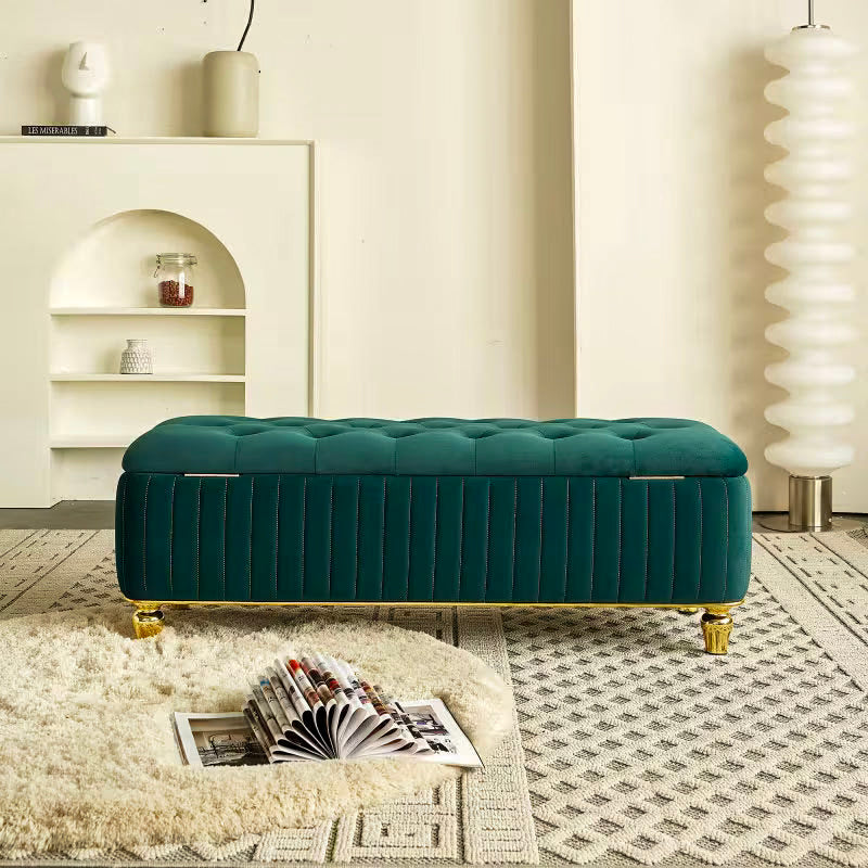 Front view of the green tufted storage bench with vertically channeled sides and gold-tone feet