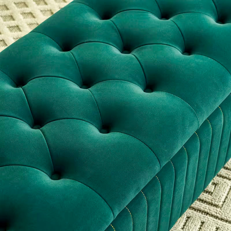 Close view of the deep green upholstery and button tufting on the padded lid