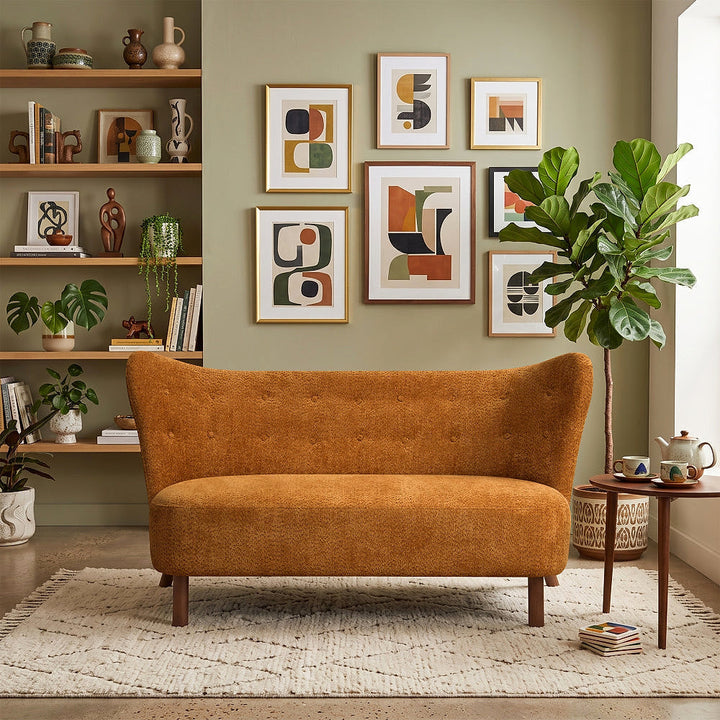 Front view of the caramel curved-back chenille loveseat styled on a cream rug beneath a gallery wall.