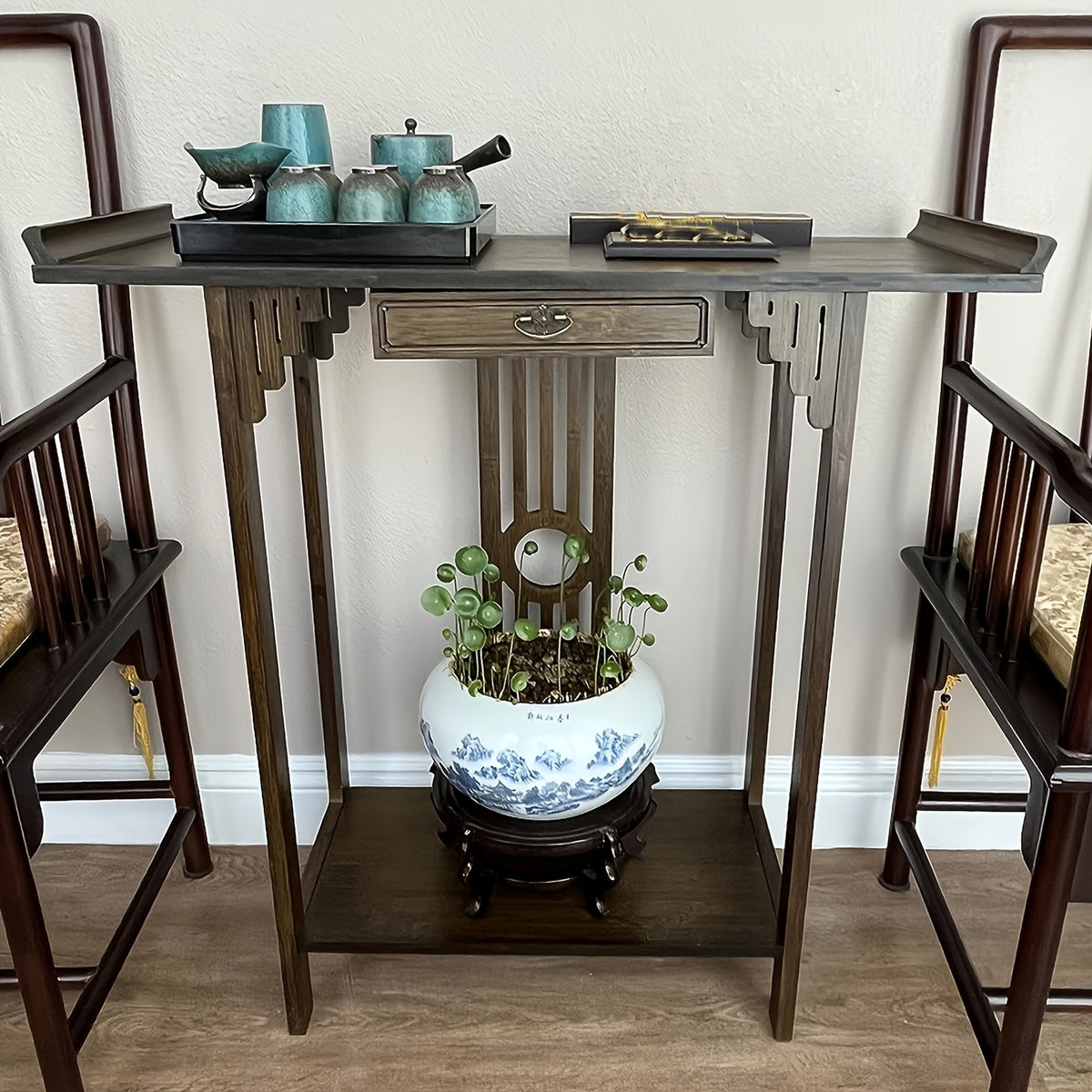 Front view of the brown bamboo console displayed between two chairs.