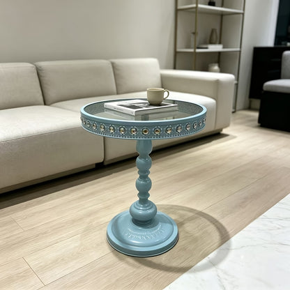 Light blue round table beside a sofa with a book and cup on top.