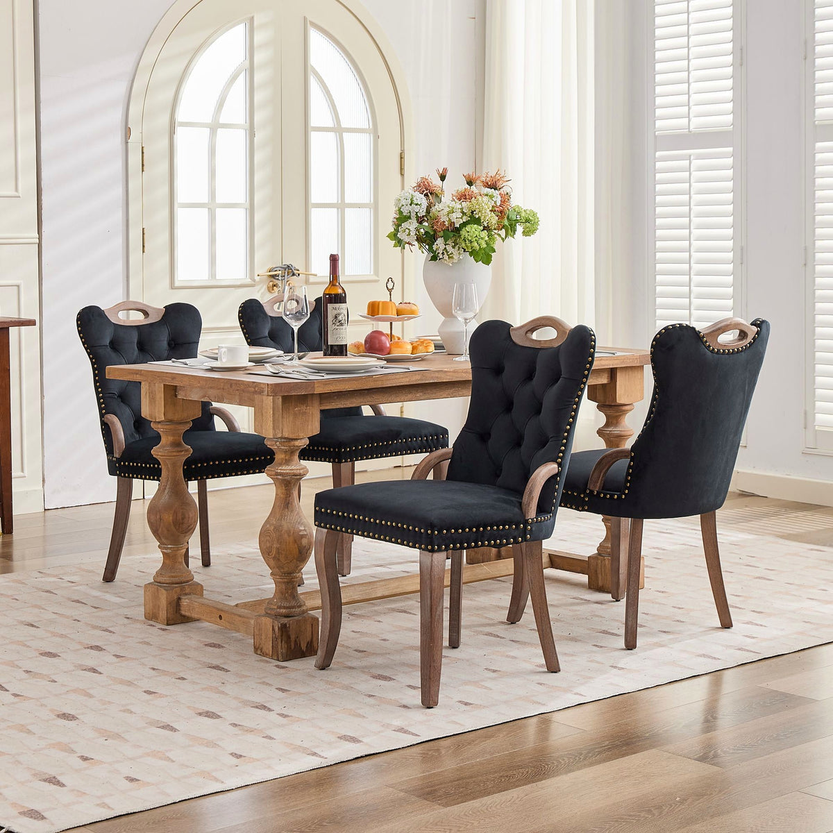 Black velvet dining chair with a tufted back, wood handle, and curved wood legs