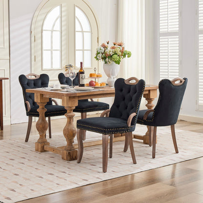 Black velvet dining chair with a tufted back, wood handle, and curved wood legs