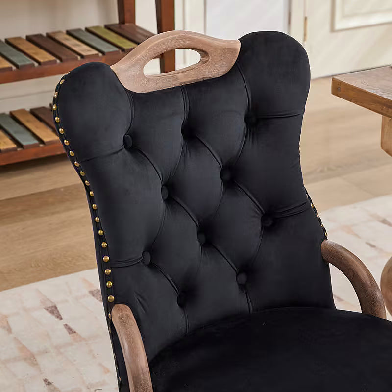 Black velvet dining chair with a tufted back, wood handle, and curved wood legs