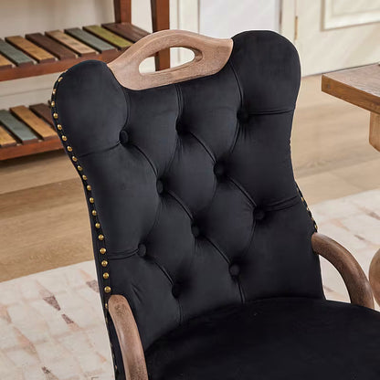 Black velvet dining chair with a tufted back, wood handle, and curved wood legs