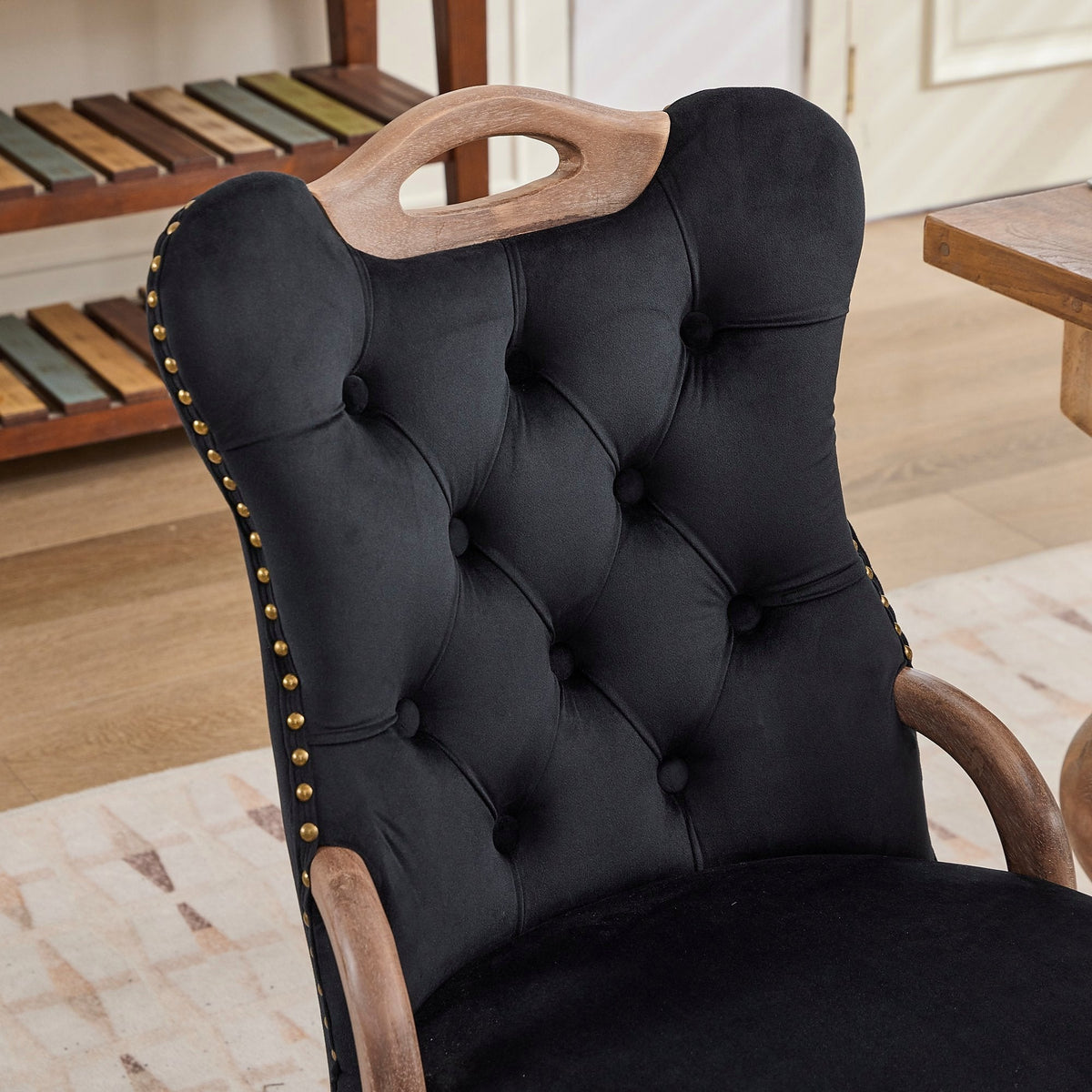 Black velvet dining chair with a tufted back, wood handle, and curved wood legs