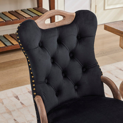 Black velvet dining chair with a tufted back, wood handle, and curved wood legs