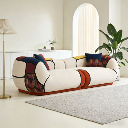 Angled view of the curved chenille sofa showing its rounded arms and rust, navy and patterned accents.