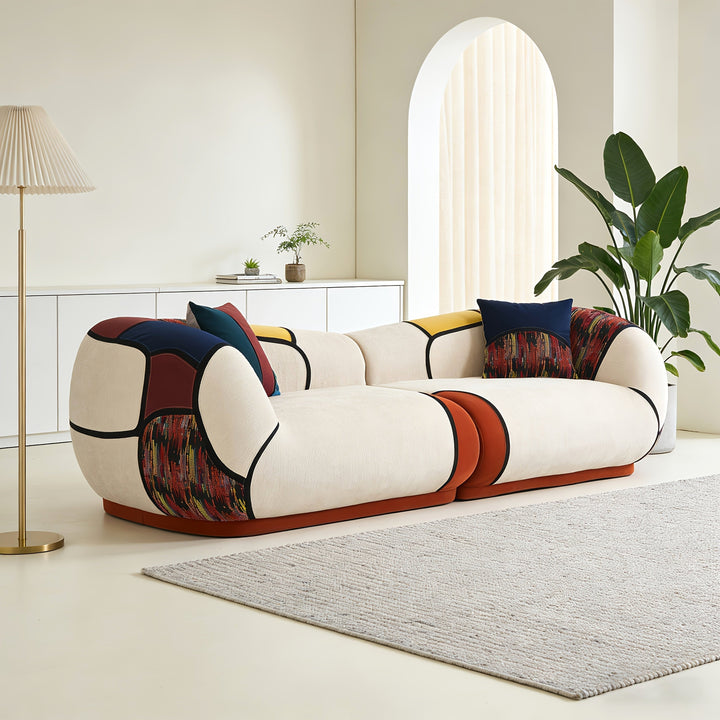 Angled view of the curved chenille sofa showing its rounded arms and rust, navy and patterned accents.