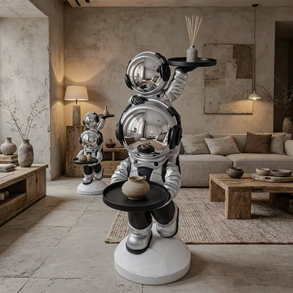Silver astronaut side table with two black trays and mirrored visors in a neutral living room