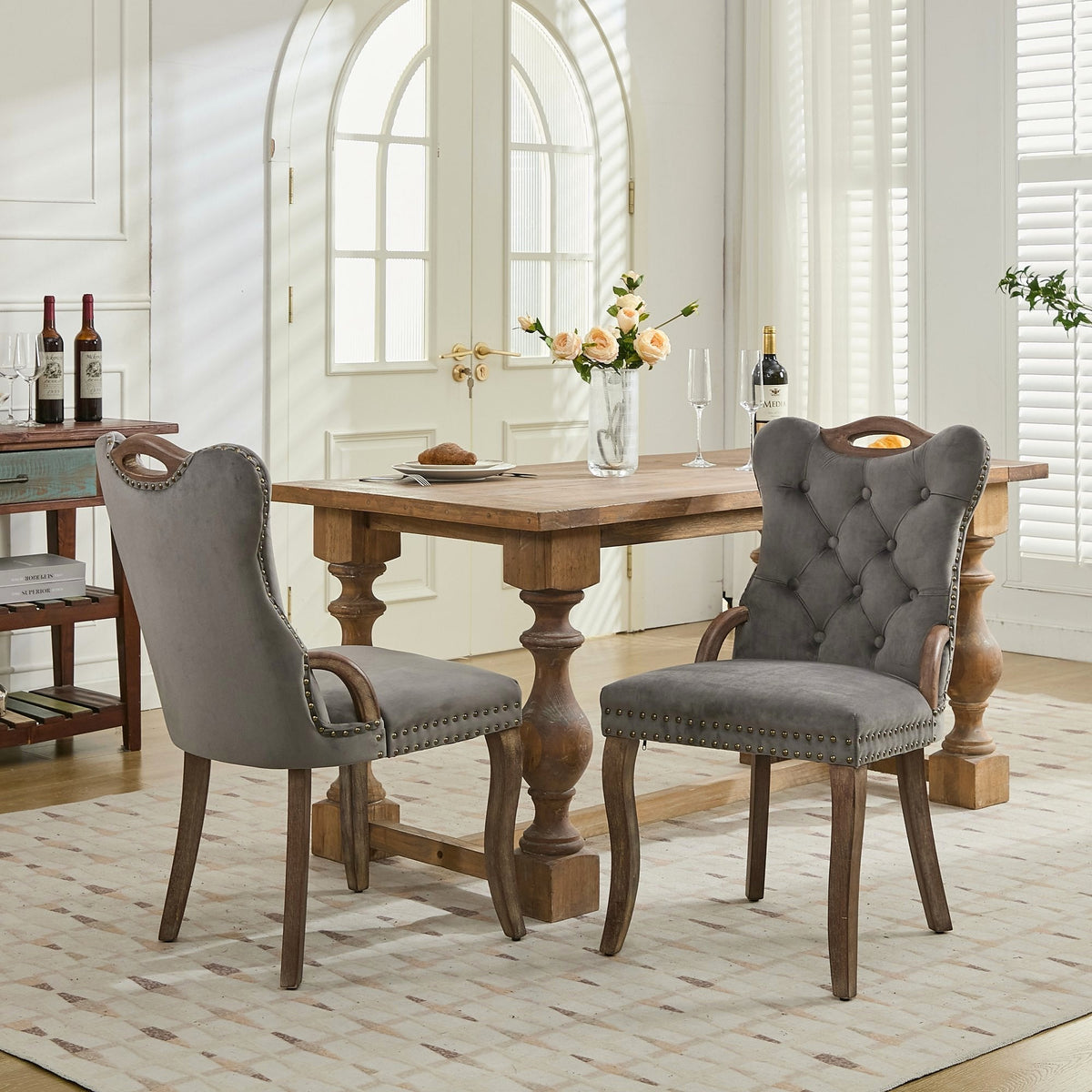 Gray velvet dining chair with a tufted back, wood handle, and curved wood legs