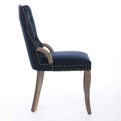 Black velvet dining chair with a tufted back, wood handle, and curved wood legs