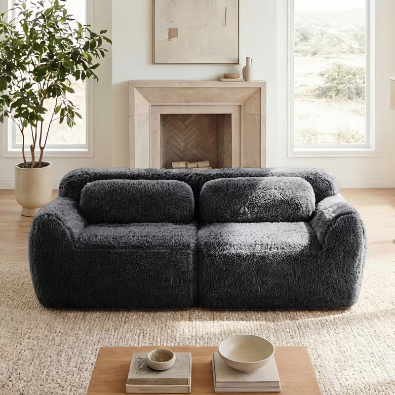 Plush Modular Two-Seat Sofa — dark grey sofa beside a fireplace.