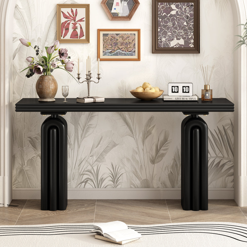 Black console with layered tabletop and arched pedestal supports styled beneath framed art.