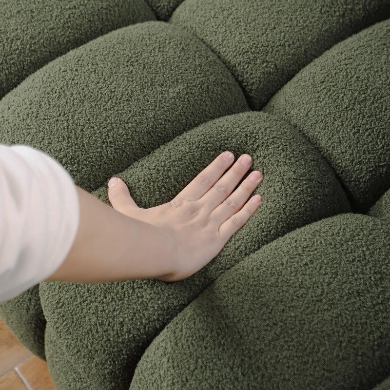 Close-up of a hand pressing the olive green sofa cushion