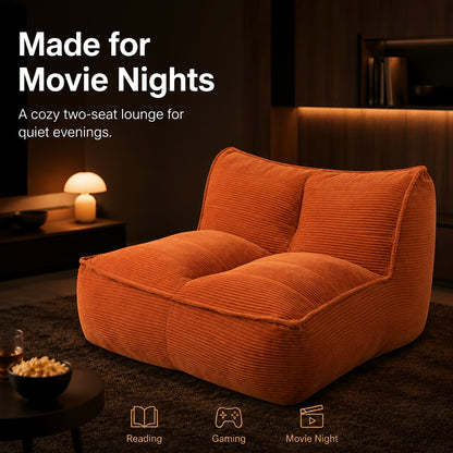 Orange corduroy floor sofa shown in a movie-night setting