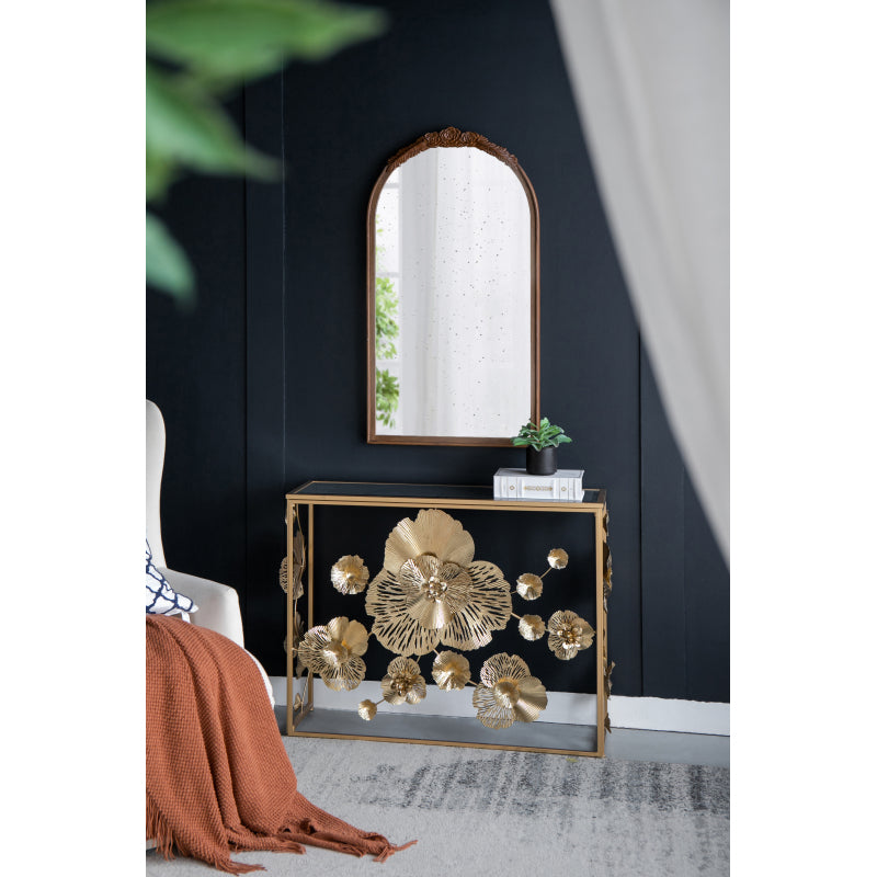 Gold floral console beneath an arched mirror in a living room.