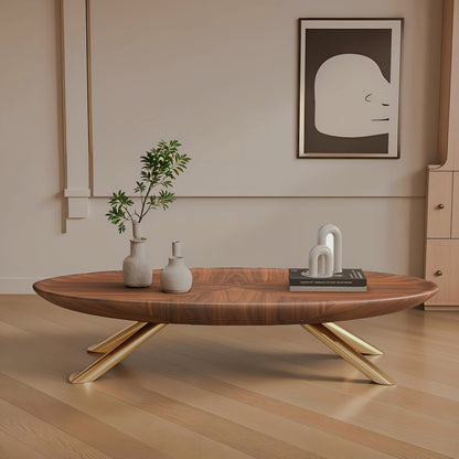 Oval wood-look coffee table with gold-tone crossed legs in a beige living room