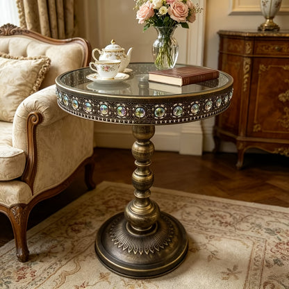 Bronze round side table styled with flowers and a teacup beside a sofa.