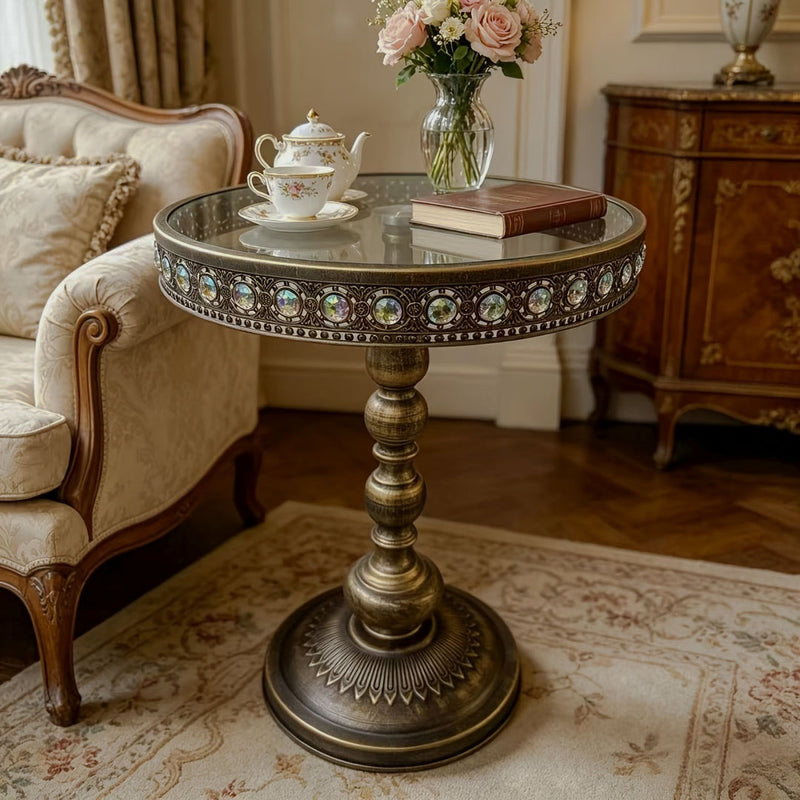 Bronze round side table styled with flowers and a teacup beside a sofa.
