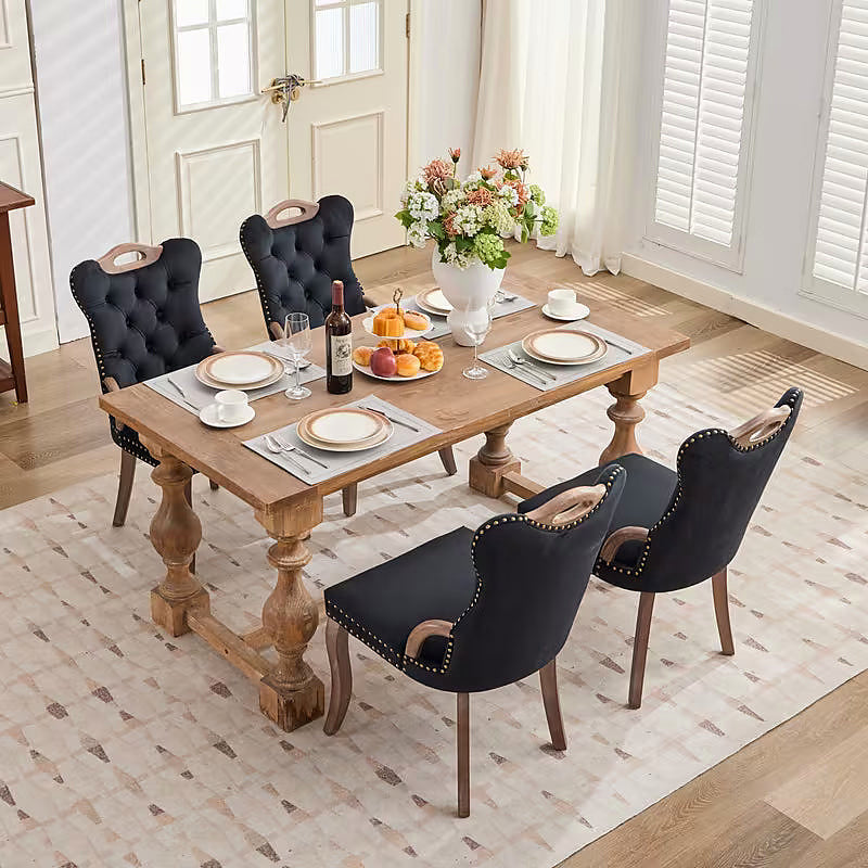 Black velvet dining chair with a tufted back, wood handle, and curved wood legs