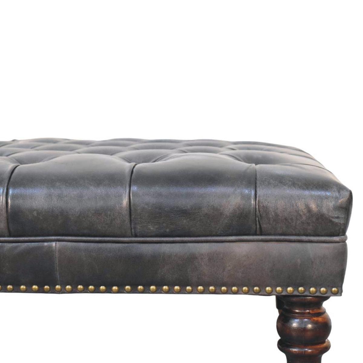Close-up of black upholstery, nailhead trim and a turned leg
